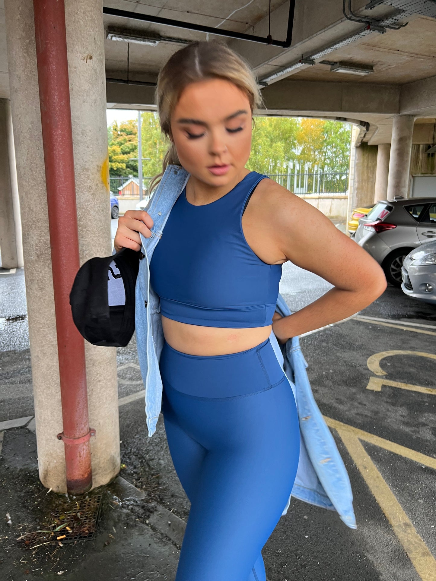 Girl wearing blue sports bra and leggings from vocus vit. She is putting on a denim jacket and hat. Vocus vit is a sustainable women's activewear brand that uses recycled materials and ethical manufacturing. Based in Northern Ireland. Shipping worldwide.Sizes XS (8) TO XXL (18).