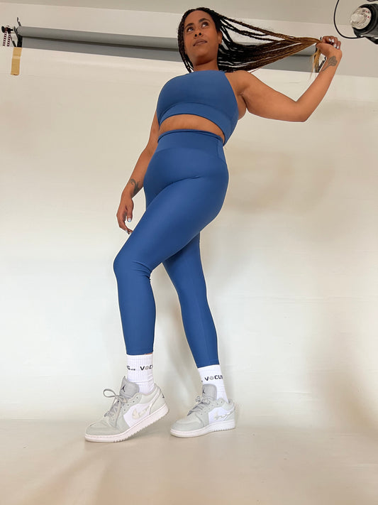 Girl holding onto her box braids and posing. she is wearing blue sports bra and leggings from Vocus vit. pairs with the crew socks. Vocus vit is a sustainable women's activewear brand that uses recycled materials and ethical manufacturing. Based in Northern Ireland. Shipping worldwide.Sizes XS (8) TO XXL (18).
