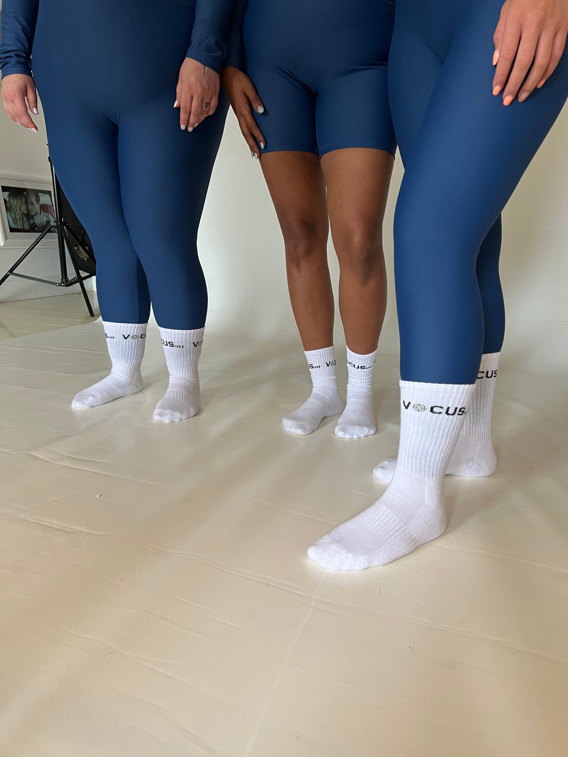 The legs of 3 girls wearing Vocus Vit leggings and shorts with crew socks. Vocus vit is a sustainable women's activewear brand that uses recycled materials and ethical manufacturing. Based in Northern Ireland. Shipping worldwide.