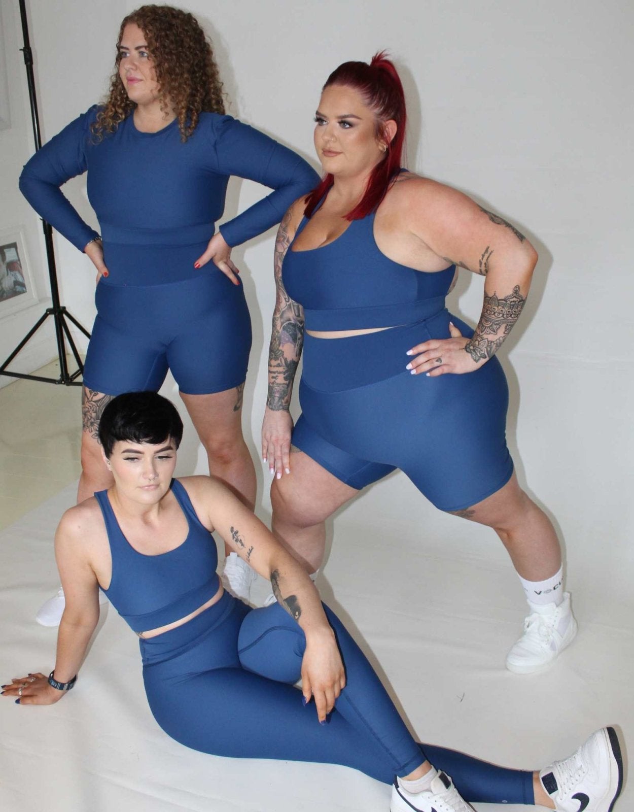 3 girls posing wearing Vocus Vit blue activewear. They are all very happy. 2 girls standing and 1 on the floor. Vocus vit is a sustainable women's activewear brand that uses recycled materials and ethical manufacturing. Based in Northern Ireland. Shipping worldwide.Sizes XS (8) TO XXL (18).