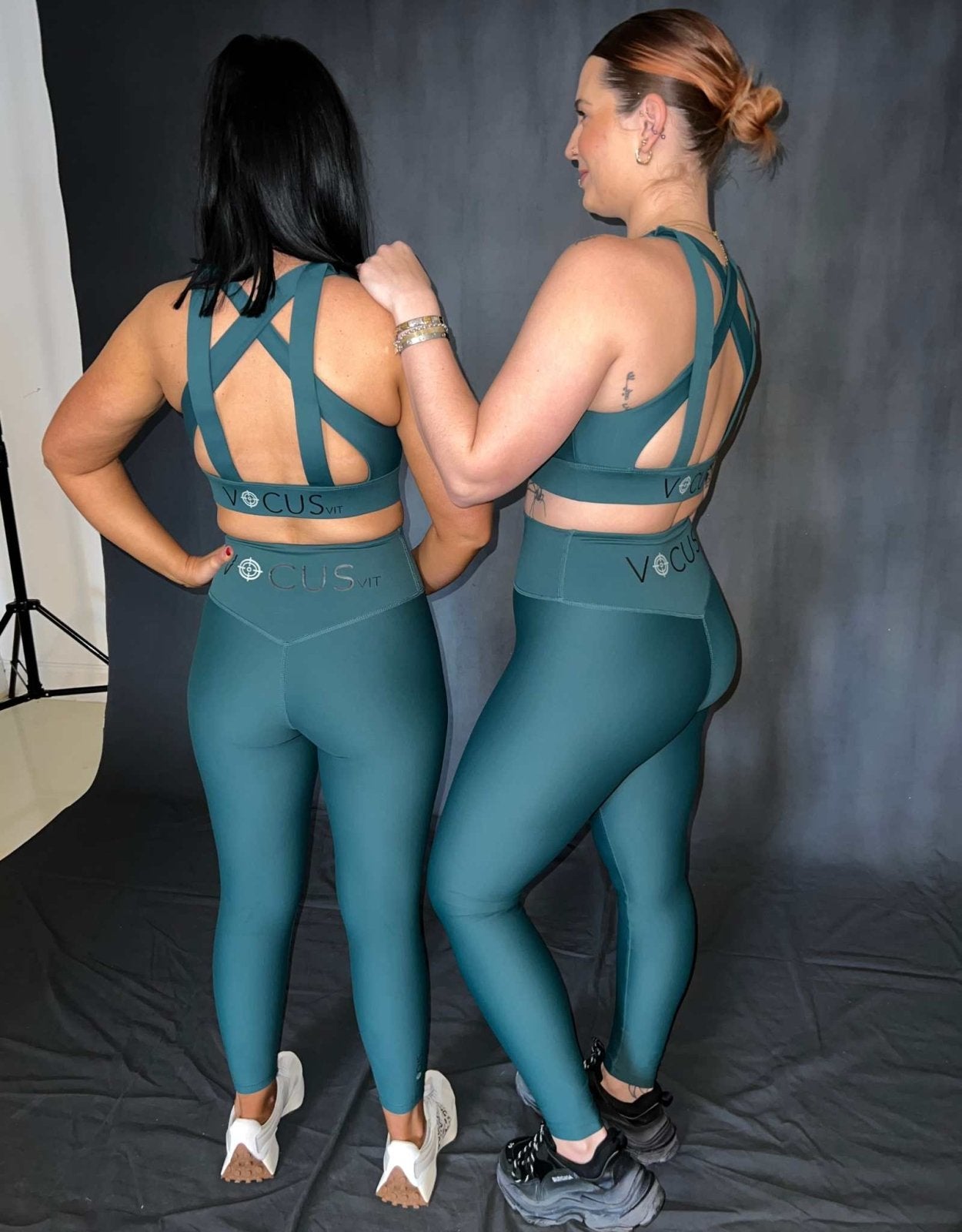 2 girls standing and modelling. One is resting her arm on the other girls shoulder. both are wearing green activewear from vocus vit. They have leggings and a cross back sports bra on. Vocus vit is a sustainable women's activewear brand that uses recycled materials and ethical manufacturing. Based in Northern Ireland. Shipping worldwide.Sizes XS (8) TO XXL (18).