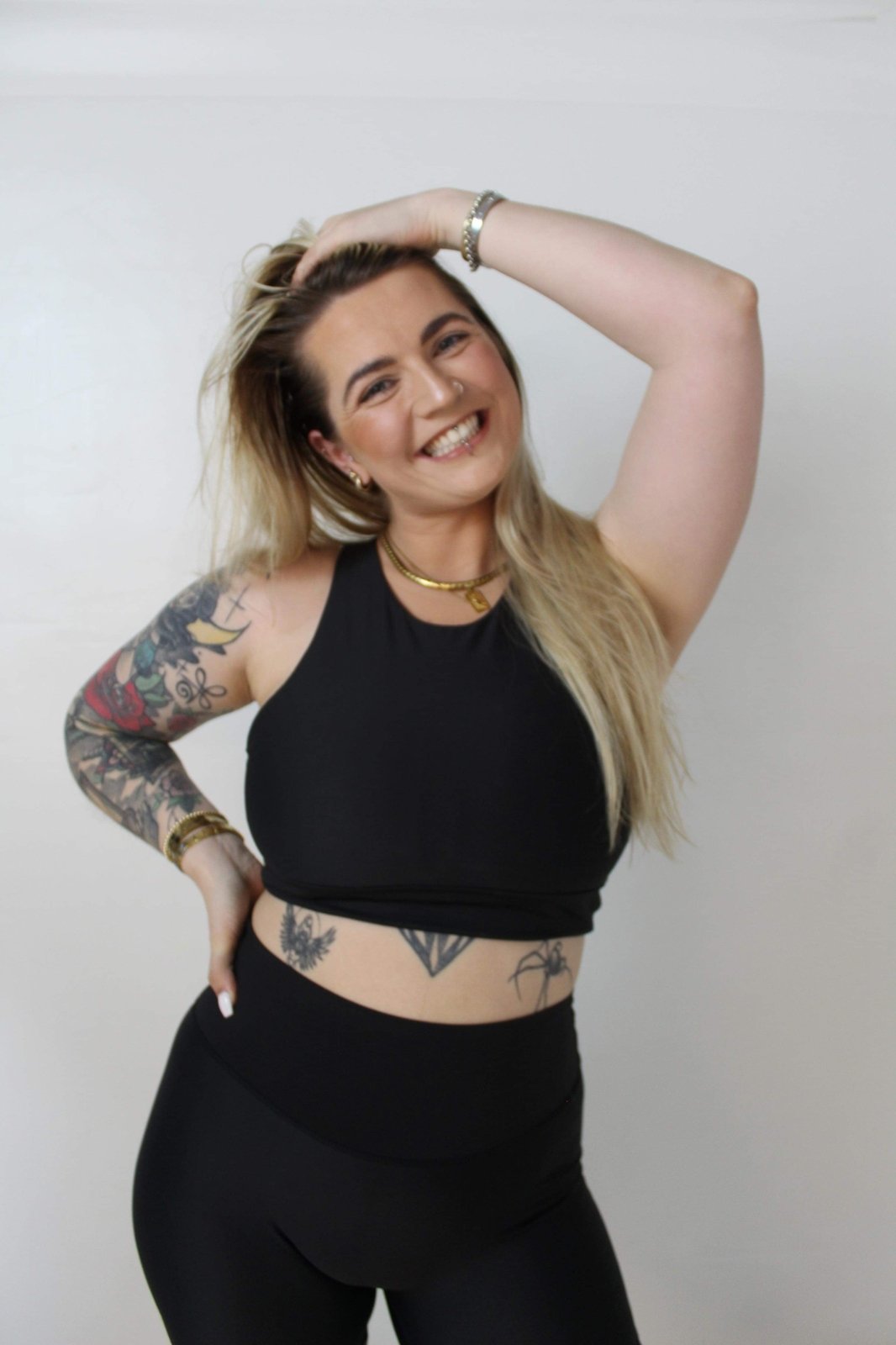 Owner of Vocus Vit, Sarah-Jane, wearing black sports bra and leggings with her hand holding her hair back from her face. Vocus vit is a sustainable women's activewear brand that uses recycled materials and ethical manufacturing. Based in Northern Ireland. Shipping worldwide.Sizes XS (8) TO XXL (18).